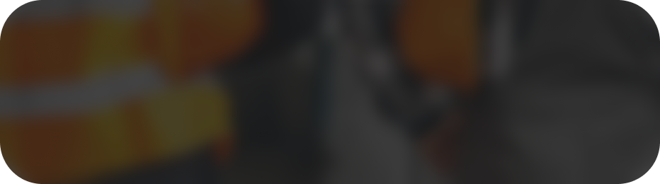 Imagen borrosa de fondo con tonos oscuros y naranjas, que sugiere un entorno de construcción o industrial.